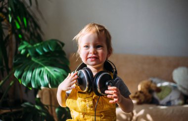 Komik küçük çocuk evde kulaklıkla eğleniyor, portre....