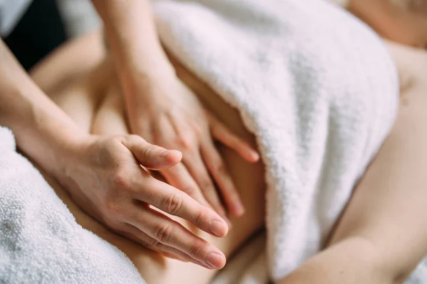 De masseur geeft een massage aan de vrouwelijke buik in de spa. — Stockfoto