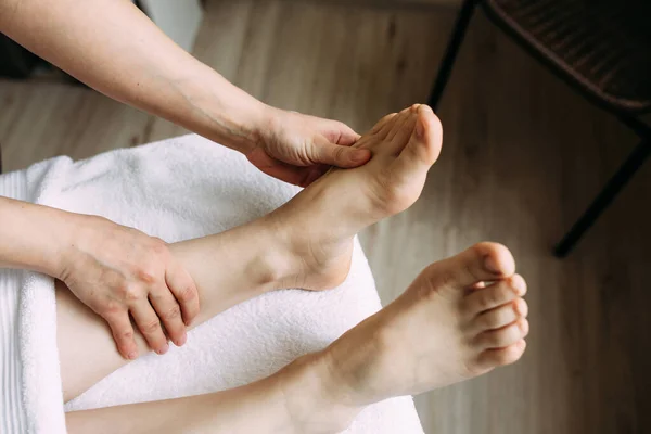 El masajista da un masaje a los pies femeninos en el spa. — Foto de Stock