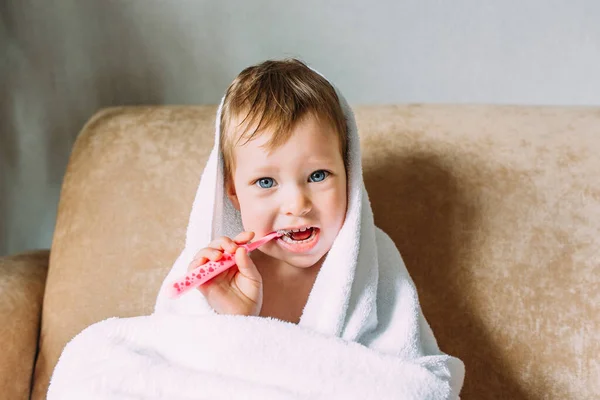 Мила дитина у великому білому рушнику. Вона чистить зуби зубною щіткою . — стокове фото