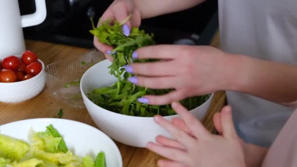 Dottern hjälper sin mamma i köket att laga hälsosam lunch och reda ut ruccola — Stockvideo