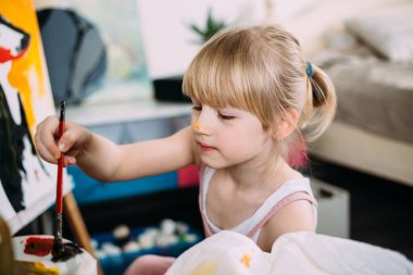 Küçük tatlı bir kız, evde akrilikle resim çiziyor.. 