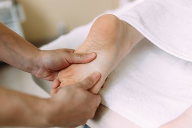 Masör kaplıcadaki kadın ayaklarına masaj yapıyor..