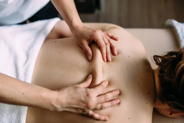 Massage therapeut doet massage op het vrouwelijk lichaam in de spa. — Stockfoto