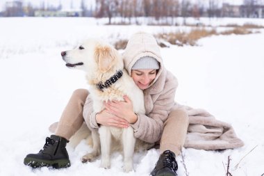 Genç güzel kadın ve onun golden retriever köpeği kışın eğleniyorlar..