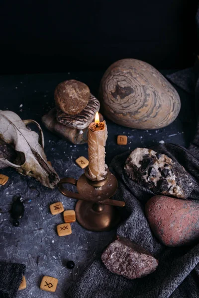 Crâne de vieux chien, bougie allumée, runes en bois et pierres sur la table des sorcières. — Photo
