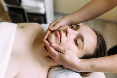 Masör kaplıcada bir kadının yüzüne masaj yapıyor..