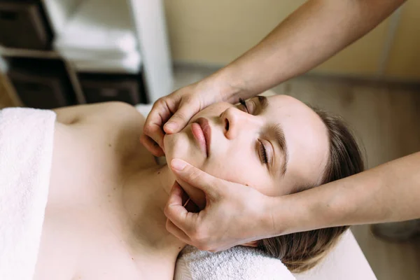 Masseur doet massage op een vrouw gezicht in de spa. — Stockfoto