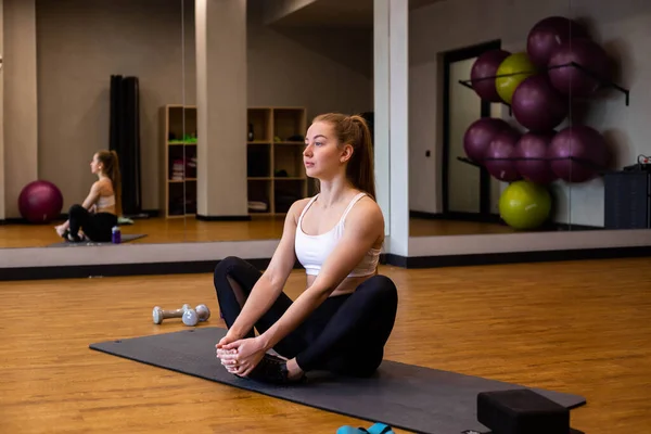 Young woman in sportswear doing stretching in indoor gym — Stock Photo, Image