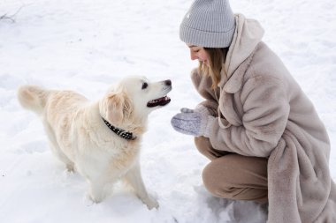 Genç güzel kadın ve onun golden retriever köpeği kışın eğleniyorlar..