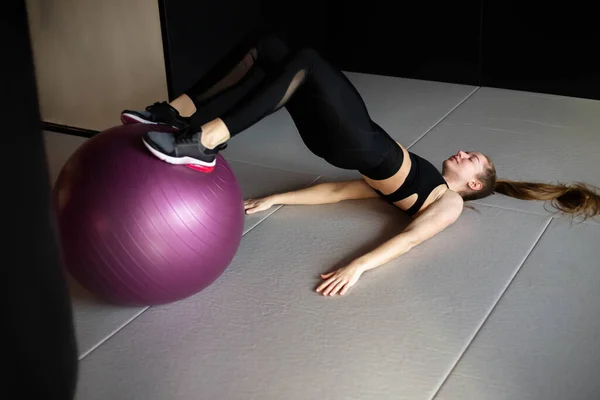 Young woman in sportswear is engaged on fitball in gym — Stock Photo, Image