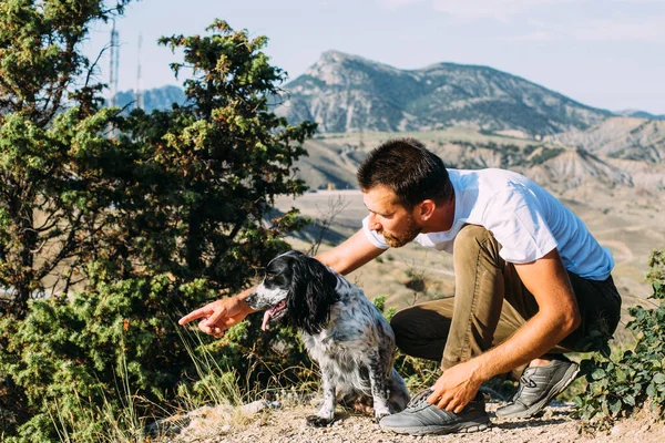 Male owner of spaniel dog walking against mountains background. — Stock Photo, Image