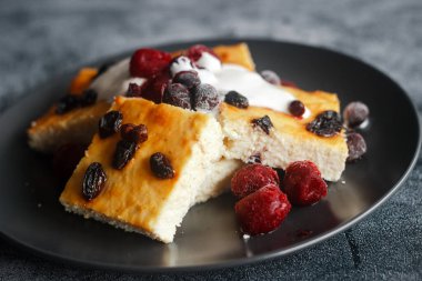 Cottage cheese casserole. Casserole with sour cream and berries. Delicious curd casserole on a concrete table