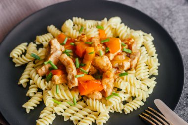 Tatlı ve ekşi soslu domuz eti ve makarna. Tabakta nefis bir sıcak yemek. Biberli domuz eti ve yeşil soğan.