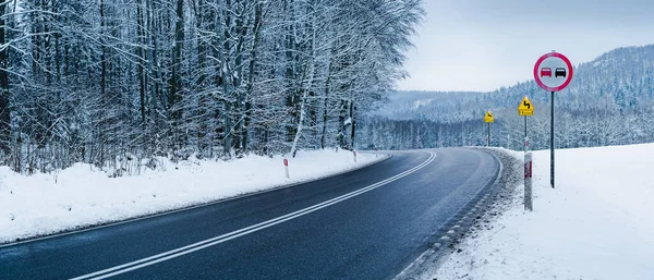 Kış manzarası, dağların arasında karla kaplı bir köy yolu. Virajlarda sollama yok.