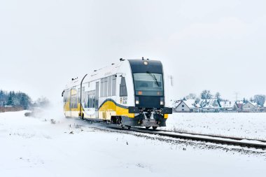 Bir kış günü karlı bir arazide demiryolu üzerinden geçen bir tren..