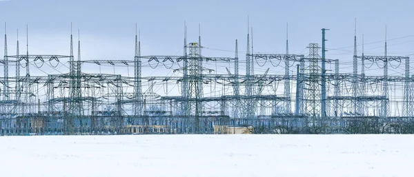 Electricity transmission lines with transformer stations. The masts are placed outside the city and transport energy in different directions, a view on a winter cloudy day.