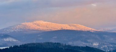 Snieznik Massif, Czarna Gora zirvesi, gün batımında dağlarda karla kaplı ormanlar.
