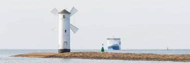 Stawa Mlyny, Swinoujscie 'de turistik bir yer, yel değirmeni şeklinde bir navigasyon işareti denizin ağzında, ufukta büyük bir feribot var..