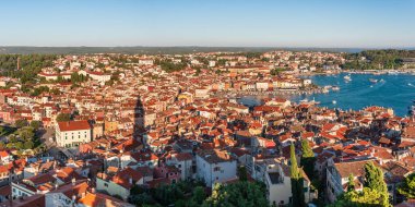 Hırvatistan 'daki Katolik Aziz Euphemia Kilisesi' nin kulesinden Rovinj sahil kenti panoraması, deniz kıyısında gün batımında küçük bir körfez manzaralı yoğun kentsel gelişim.