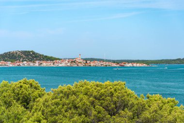 Hırvatistan 'ın Tisno kıyı kenti alçak dağlar ve mavi sularla çevrili deniz kıyısında yer alıyor. Güneşli bir günde yaz manzarasından bir manzara..