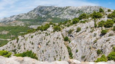 Hırvatistan 'ın sahil kenti Omis, dağların eteklerinde yer alıyor. Dağların eteklerindeki dağ yürüyüşü patikasından dağların tepesindeki Mirabela Kalesi' nin kalıntılarına kadar görülebilen bir manzara..