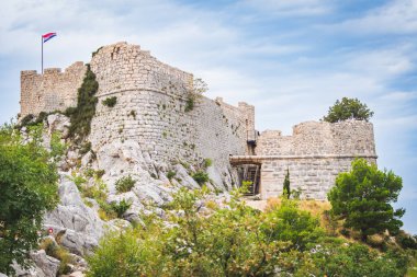Hırvatistan 'ın Omis kentindeki bir dağın tepesindeki Mirabela Kalesi harabeleri, yaz günü bir dağ yürüyüşü patikasından turistik bir manzara..