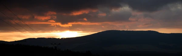 Panorama günbatımı bulutlu gökyüzü için dağların üzerinden. — Stok fotoğraf