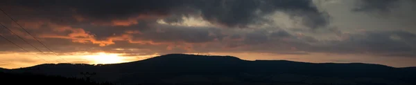 Panorama günbatımı bulutlu gökyüzü için dağların üzerinden. — Stok fotoğraf