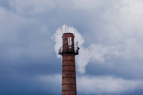 Air pollution by smoke coming out of factory chimneys. Brick pipe on sky background