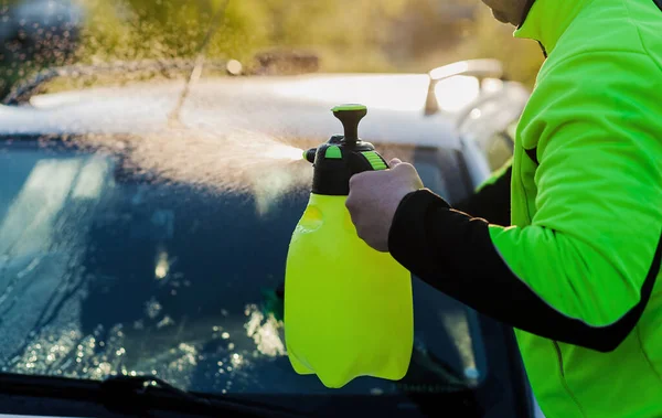 Man cleaning automobile with high pressure water at car wash outdoors