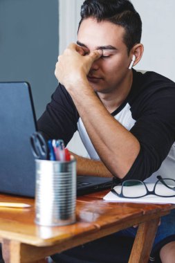 Stresli ve yorgun Kafkasyalı genç adam evinde oturuyor ve eli suratında oturuyor.