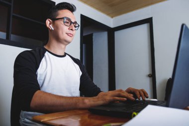 Rahat adam masaüstünde oturuyor ve evde çalışıyor. Bilgisayarına bakıyor ve daktilo yazıyor.