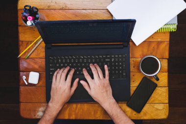 Masaüstü ve beyaz erkek ellerinin akıllı telefon ve kahveyle dizüstü bilgisayarda çalışmasının en üst görüntüsü