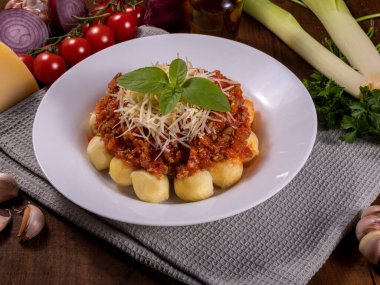 Doğal organik domates soslu bolonez gnocchi, böcek ilacı yok, rendelenmiş parmesan peyniri ve fesleğen yapraklı.