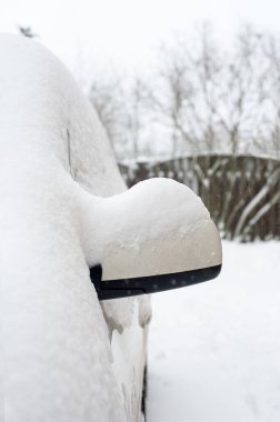 Araba aynası karla kaplı. Dikey kış dönemi görüntüsünün dışında