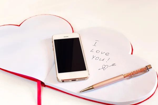 Smartphone i Valentine miłości wiadomości w sercu kształt notatnik. — Zdjęcie stockowe
