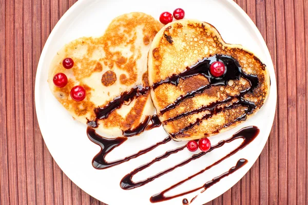 Heart shaped pancakes with chocolate sauce and cranberries. — Stock Photo, Image