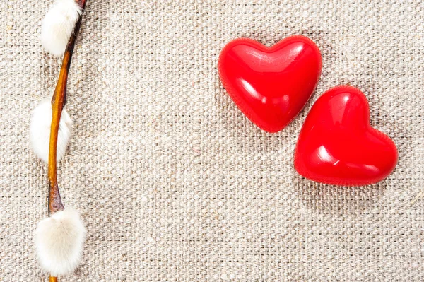 Two shiny glass love hearts with spring willow twig — Stock Photo, Image