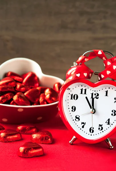Valentine love horloge rouge en forme de coeur avec des chocolats sucrés . — Photo