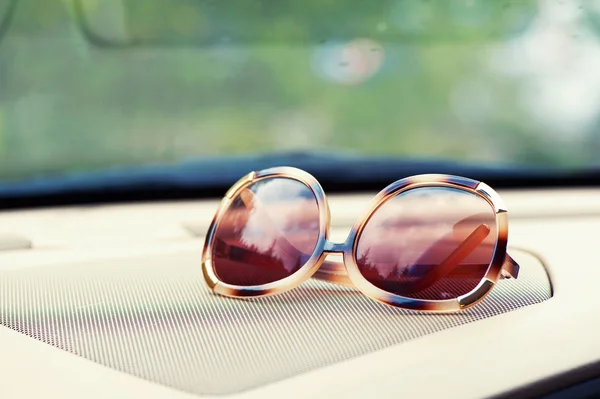 Elegant fashionable plastic women's sunglasses on interior car d — Stock Photo, Image