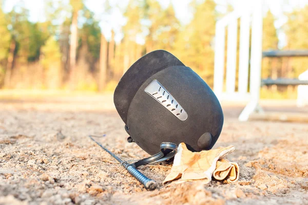 Gants de casque équestre et fouet oubliés au sol — Photo