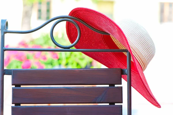 Part of elegant metal curved chair and red summer hat on patio. — Stock Photo, Image