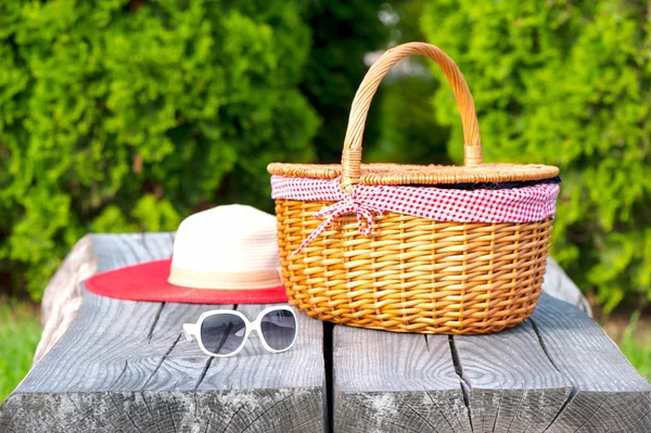 White sunglasses summer hat and wicker basket on wooden table — Stock Photo, Image