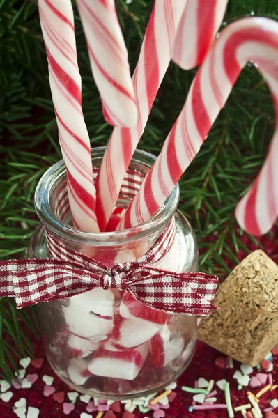 Bunch of red and white striped candy canes in glass jar on chris — Stock Photo, Image