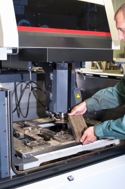 Worker examining metal detail in cnc industrial machine clipart