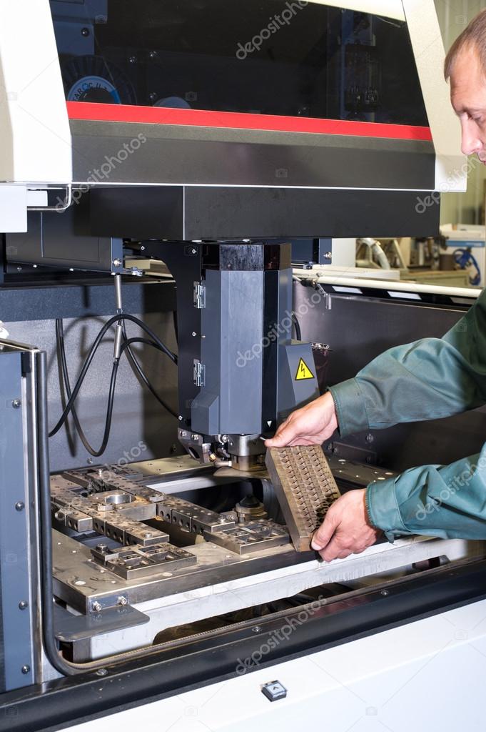 Worker examining metal detail in cnc industrial machine