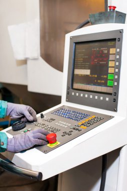 Worker hands on the control panel of a cnc programmable machine.