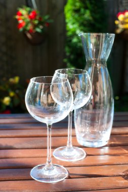 Two transparent shiny empty wineglasses and carafe in rays of su