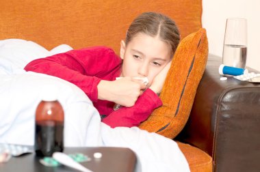 Mendil ile kanepede yatan hasta çocuk